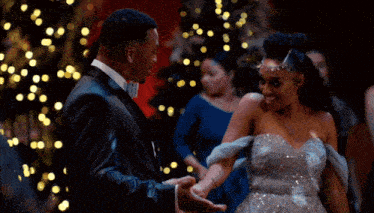 a man in a tuxedo and a woman in a gown are holding hands on a dance floor