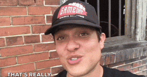 a man wearing a gameday hat says that 's really in front of a brick wall