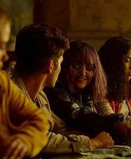 a group of people are sitting at a table and one of them has glasses on