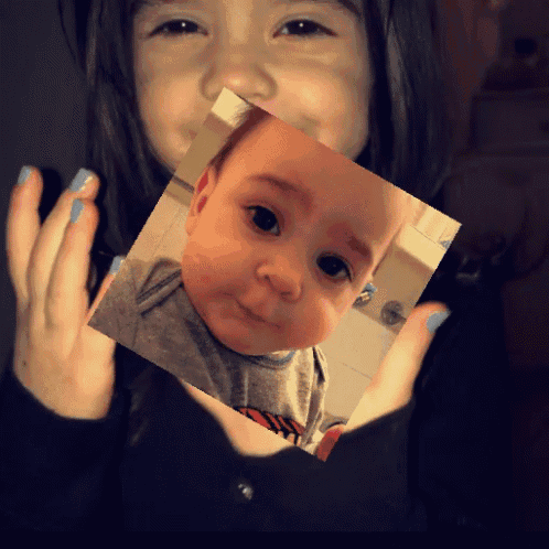 a little girl holding a picture of a baby