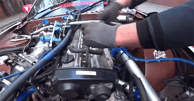 a man is working on the engine of a car with a sticker on the windshield that says ' triumph '