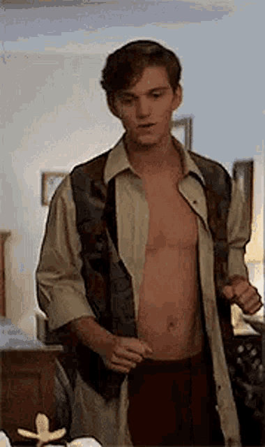 a shirtless man is standing in a living room taking off his shirt .