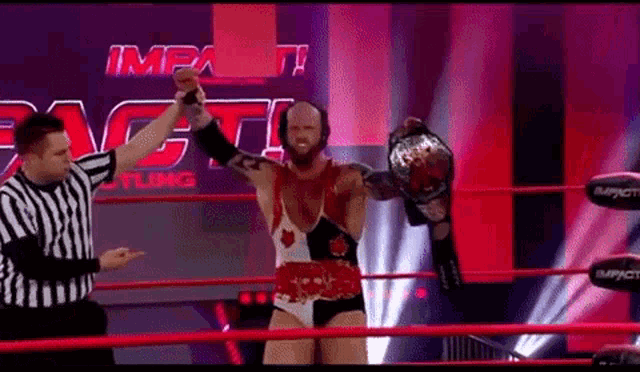 a man in a wrestling ring is holding a championship belt .