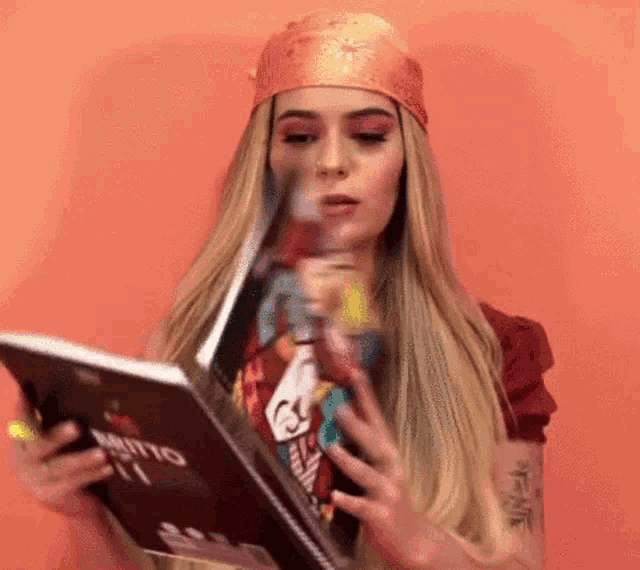 the woman is wearing a bandana and reading a book .