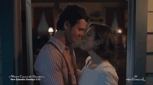 a man and woman kissing in front of a sign that says " when calls the heart "