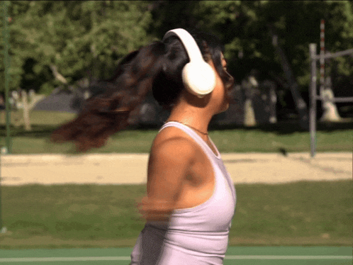 a woman wearing headphones is standing on a tennis court with her hair in a ponytail