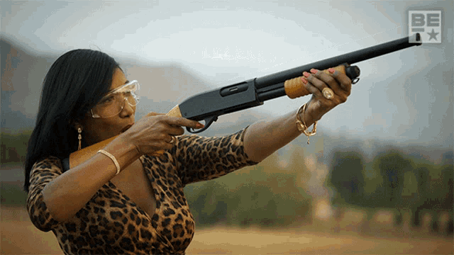 a woman wearing a leopard print shirt is pointing a shotgun at the camera