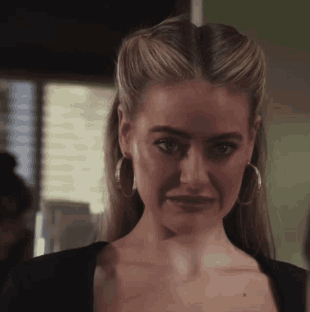 a woman wearing hoop earrings and a black top