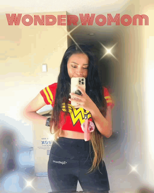 a woman taking a picture of herself in a mirror with the words wonderwomom written above her