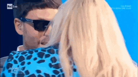a man and a woman are kissing on a television show . the woman is wearing a leopard print dress .