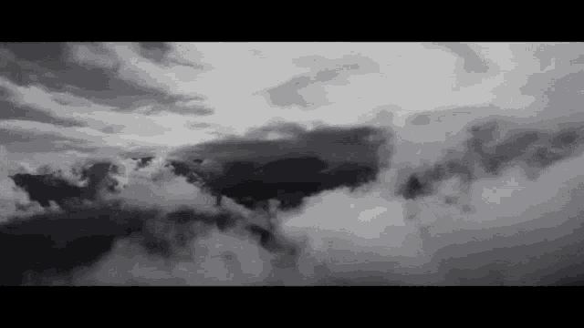a black and white photo of a mountain range surrounded by clouds .