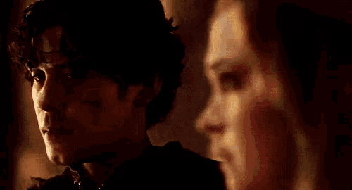 a close up of a man and a woman looking at each other in a dark room .