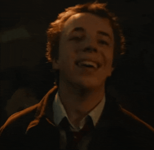 a man in a suit and tie is laughing with his mouth open .