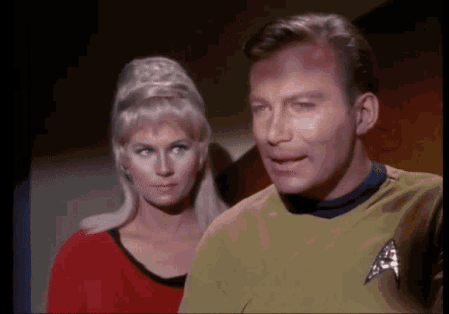 a man and a woman are standing next to each other and the man is wearing a yellow shirt with the letter a on it