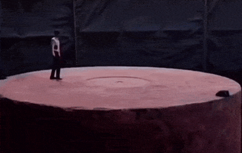 a man in a white shirt is standing in a circle with his arms up