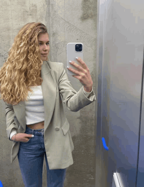 a woman taking a picture of herself in a mirror with her phone