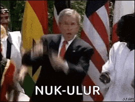 a man in a suit and tie is dancing in front of a group of people with flags .