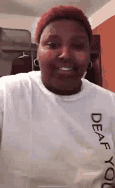 a woman with red hair is wearing a white t-shirt that says `` deaf for you '' .