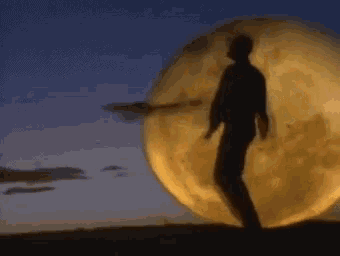 a man is standing in front of a full moon at night