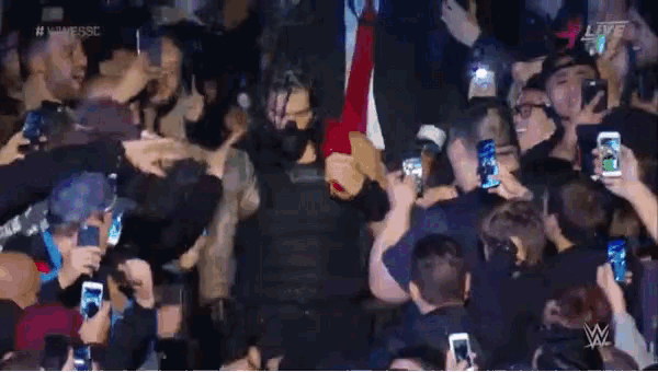 a man in a mask is surrounded by a crowd of people with their cell phones and the words live on the bottom