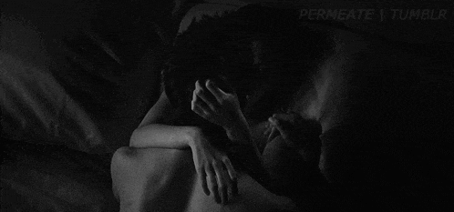 a black and white photo of a man kissing a woman on the neck .
