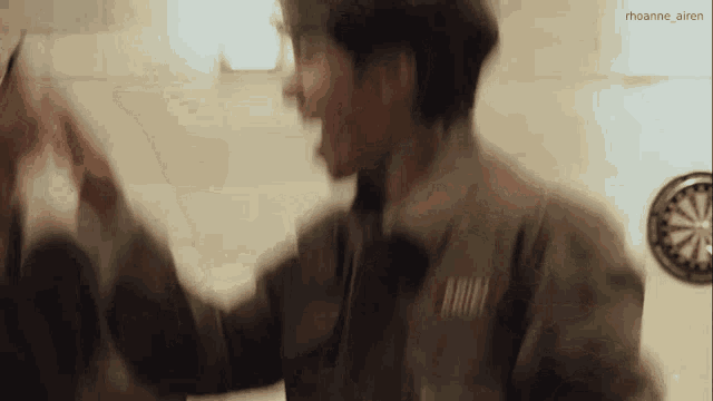 a man is giving another man a high five while standing next to a dart board .