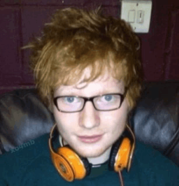 a man wearing glasses and orange headphones is smiling