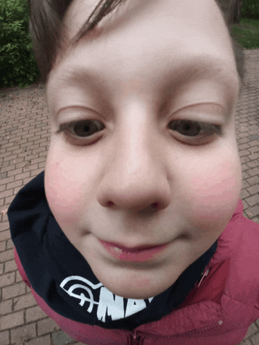 a close up of a child 's face wearing a pink jacket and a sweatshirt that says gnm
