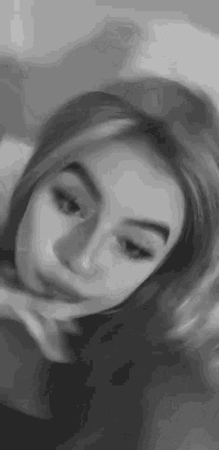 a black and white photo of a woman 's face with her hand on her chin .