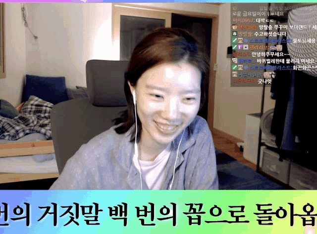 a woman wearing ear buds is smiling in front of a screen with korean writing