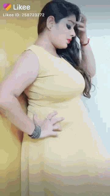 a woman in a yellow dress is leaning against a yellow wall .
