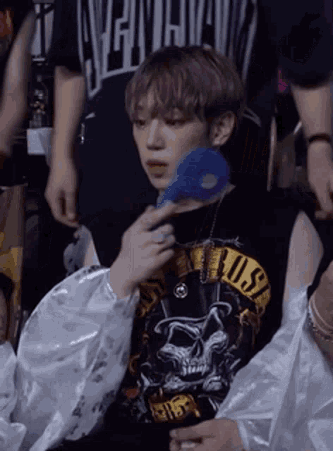a young man wearing a guns n ' roses shirt is holding a blue sponge .