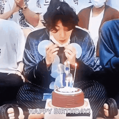 a man is blowing out candles on a birthday cake while wearing a face mask .