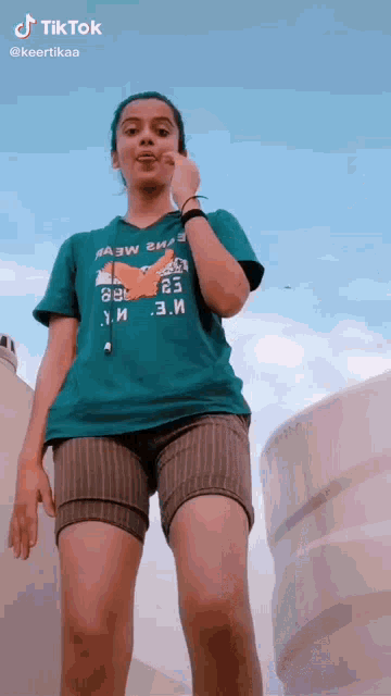 a woman wearing a green shirt with the number 23 on it is standing in front of a blue sky