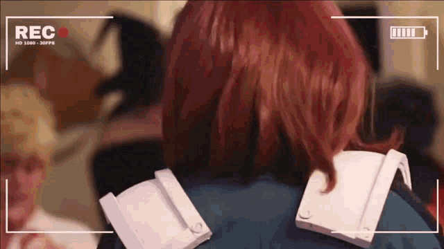 a person with red hair is standing in front of a camera that says rec