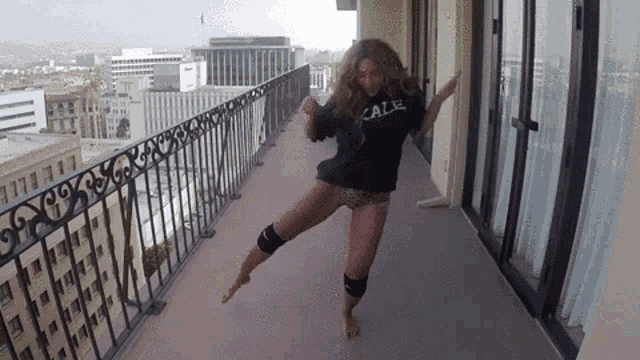 a woman is dancing on a balcony wearing a shirt that says calif .