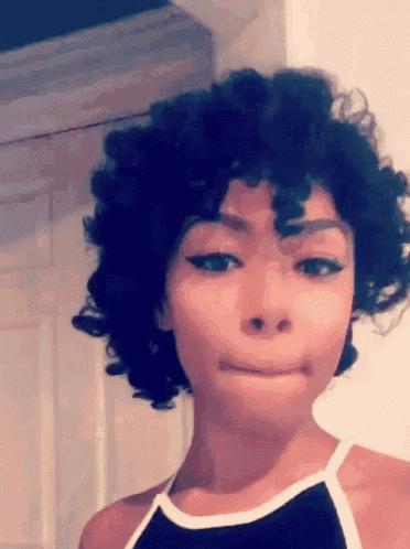 a woman with short curly hair is making a funny face .