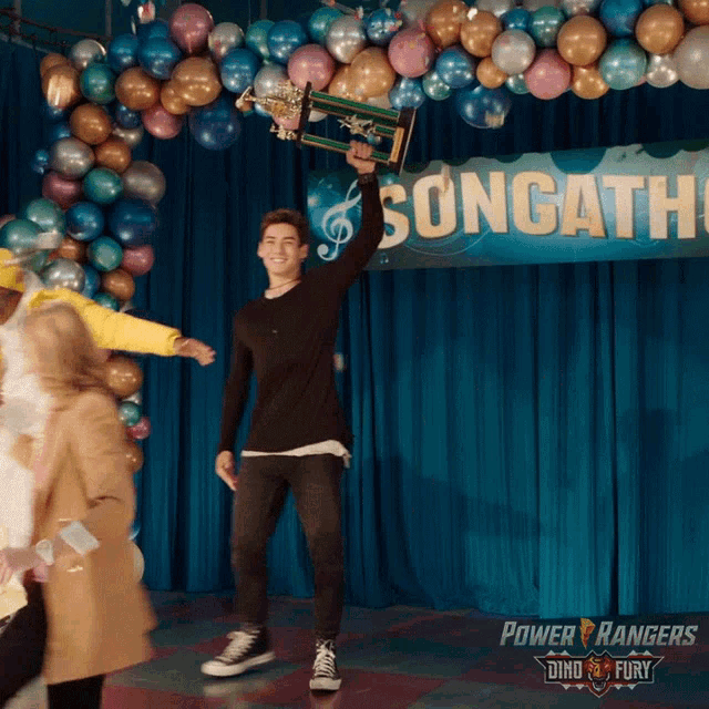 a man is holding a trophy in front of a sign that says songatha