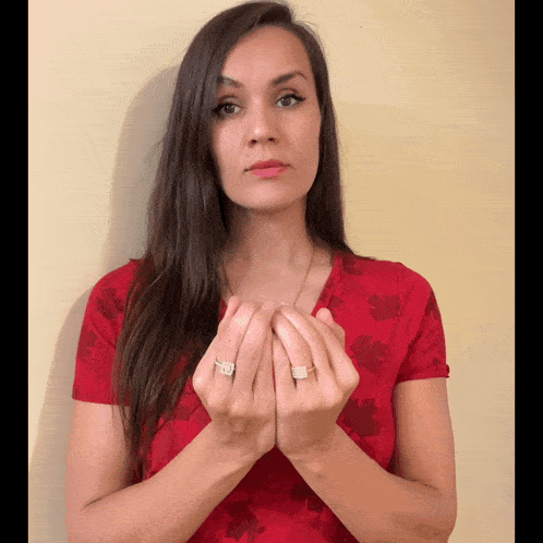 a woman wearing a red shirt with leaves on it is holding her hands together