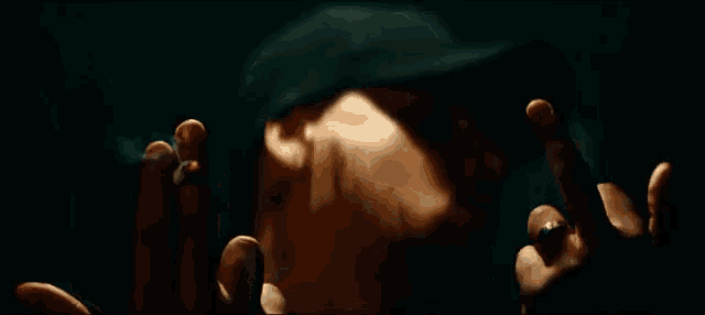 a man in a hat is smoking a cigarette and giving the middle finger
