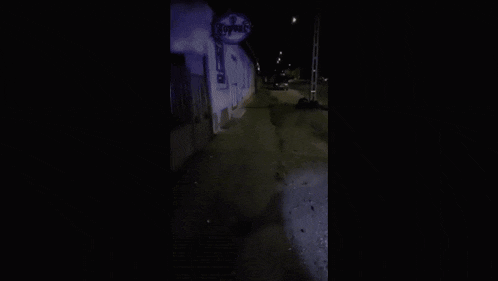 a man is walking down a street at night with a flashlight .