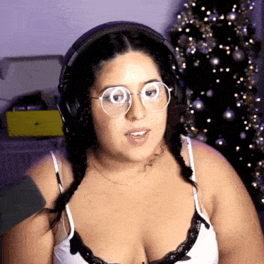 a woman wearing glasses and headphones with a christmas tree in the background