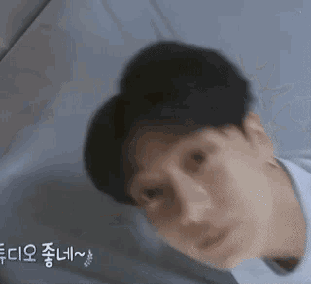a close up of a man 's face with a blurry background and korean writing on it .