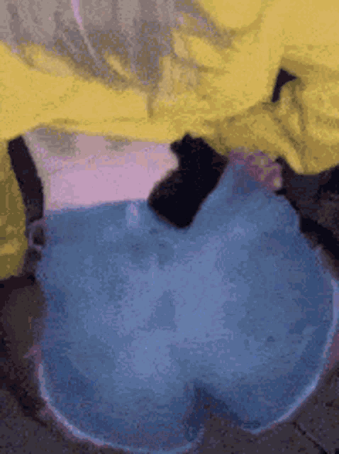 a person in a yellow jacket and blue jeans is laying on the ground