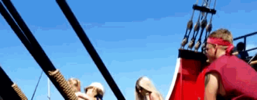 a man wearing a red headband sits on the deck of a boat