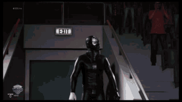 a man in a mask stands in front of a green exit sign