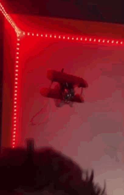 a toy airplane is flying through a red lighted room .