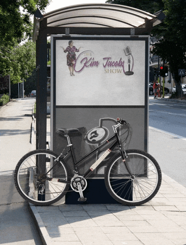 a bicycle is parked in front of a billboard for the kim jacobs show