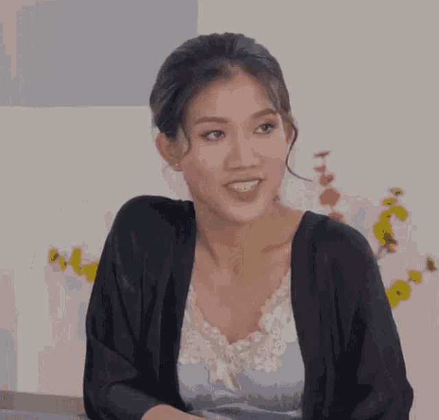 a woman wearing a black cardigan and a blue top smiles for the camera