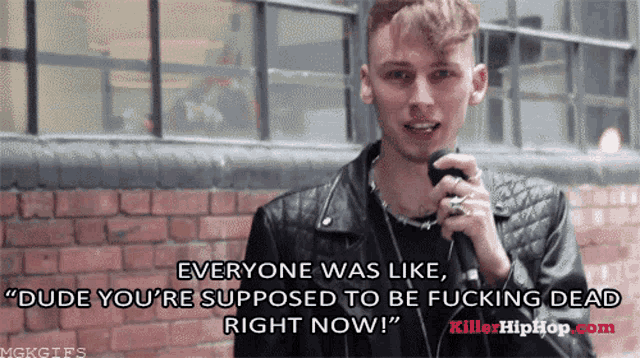 a man in a leather jacket is holding a microphone and says everyone was like